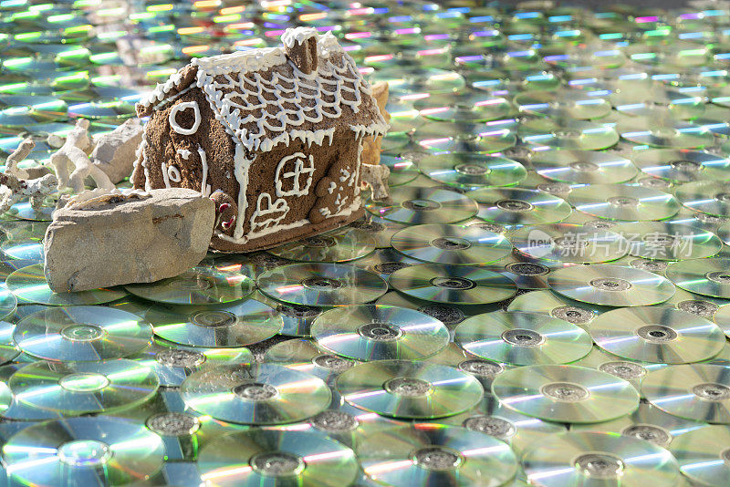 甜蜜的房子在岩石上的贝壳和阳光反射，如在水中的彩色CD/DVD作为纹理背景